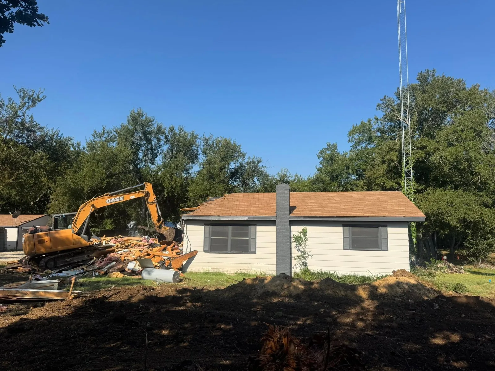 A tracked excavator taking down a single-storey house
